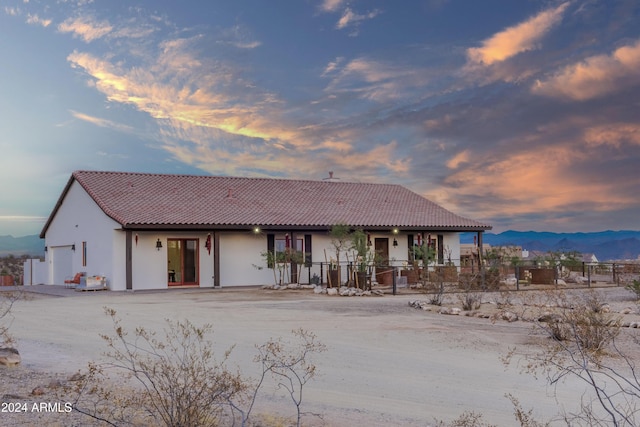 back house at dusk featuring a mountain view and a garage