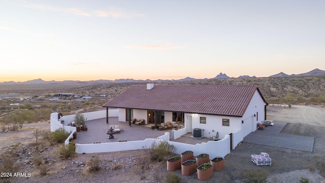 back house at dusk with a mountain view and central AC unit