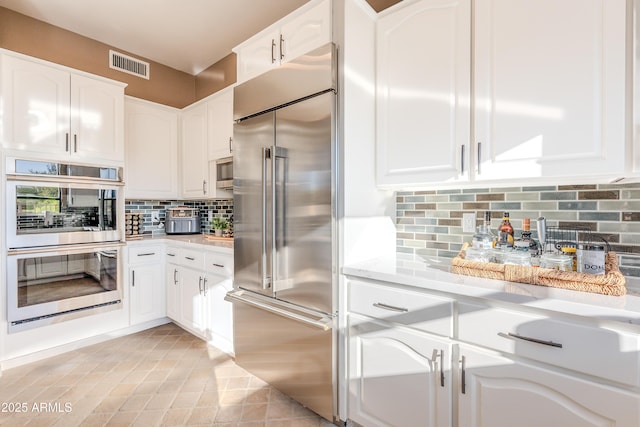 10772 E Running Deer Trl, Scottsdale, AZ 85262 - kitchen with appliances with stainless steel finishes, decorative backsplash, light countertops, white cabinets, and light tile patterned floors