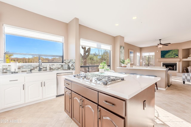 10772 E Running Deer Trl, Scottsdale, AZ 85262 - kitchen with appliances with stainless steel finishes, a kitchen island, a ceiling fan, a fireplace, and backsplash