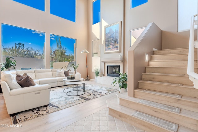 10772 E Running Deer Trl, Scottsdale, AZ 85262 - living area featuring a high ceiling, wood finished floors, stairway, a fireplace with raised hearth, and plenty of natural light