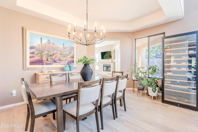 10772 E Running Deer Trl, Scottsdale, AZ 85262 - dining area featuring a raised ceiling, a chandelier, light wood-style floors, and baseboards