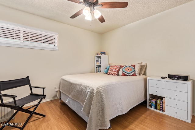 bedroom featuring a textured ceiling, light hardwood / wood-style flooring, and ceiling fan