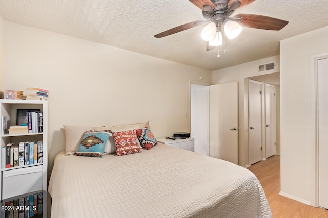 bedroom with ceiling fan, light hardwood / wood-style flooring, and a textured ceiling