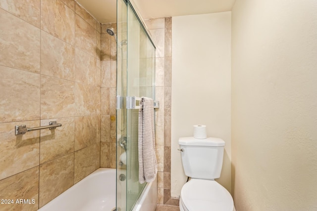 bathroom with combined bath / shower with glass door and toilet