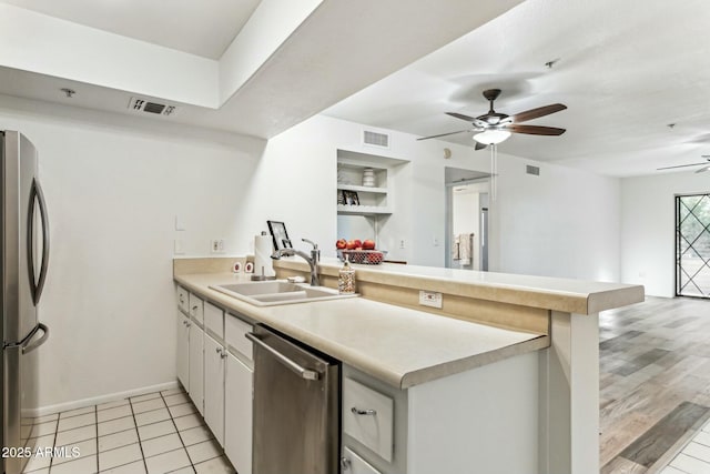 kitchen featuring kitchen peninsula, ceiling fan, appliances with stainless steel finishes, sink, and white cabinetry