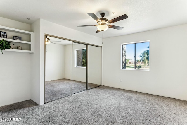 unfurnished bedroom featuring carpet floors, a closet, and ceiling fan