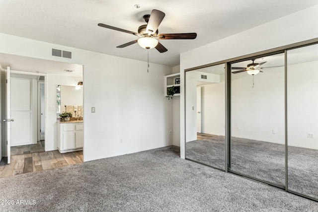 unfurnished bedroom featuring ceiling fan, a closet, and light carpet