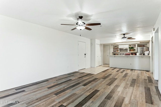 unfurnished living room featuring wood-type flooring and ceiling fan