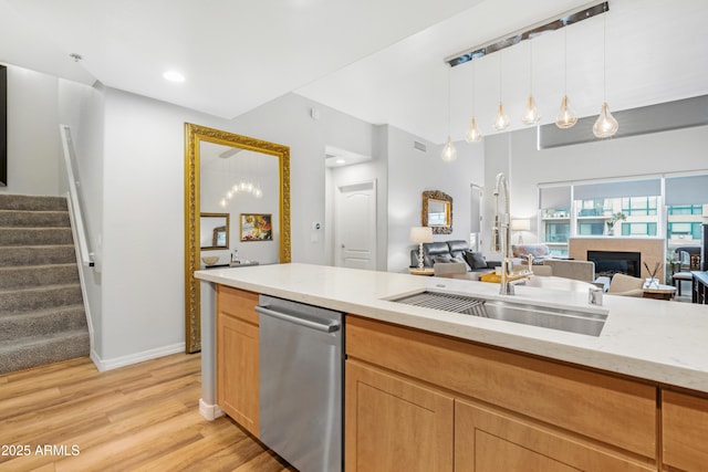 kitchen with pendant lighting, dishwasher, sink, light stone counters, and light hardwood / wood-style flooring