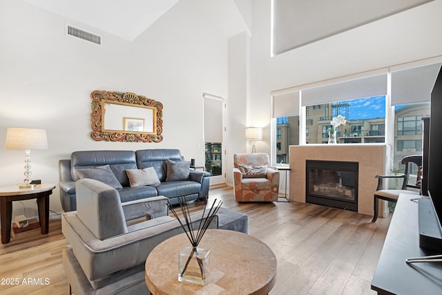 living room featuring a fireplace, a high ceiling, and light wood-type flooring