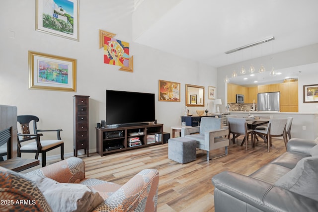 living area featuring track lighting, light wood-style flooring, and baseboards