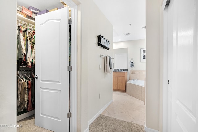 corridor with light tile patterned floors, light colored carpet, visible vents, and baseboards