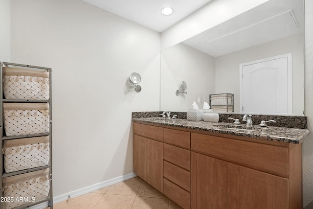 bathroom featuring a sink, baseboards, double vanity, and tile patterned flooring