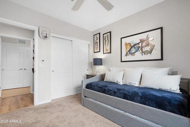 bedroom featuring light colored carpet, a closet, and ceiling fan