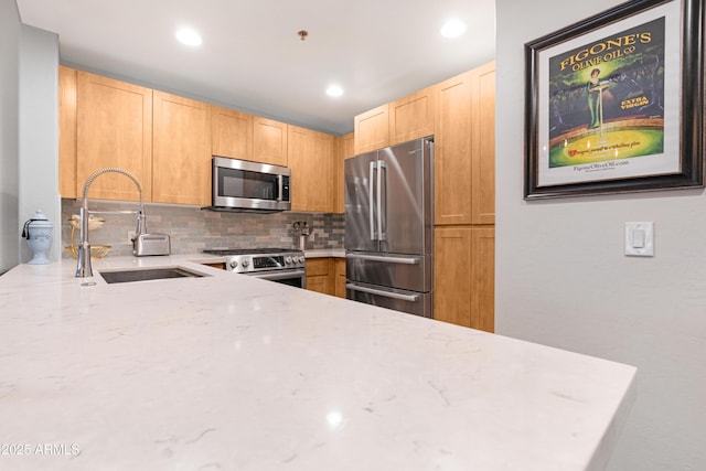 kitchen featuring a sink, stainless steel appliances, light stone counters, and light brown cabinets