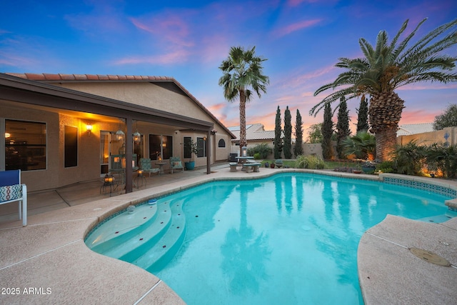 pool at dusk featuring fence, a fenced in pool, and a patio