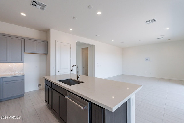 kitchen featuring dishwasher, sink, light stone countertops, and a center island with sink