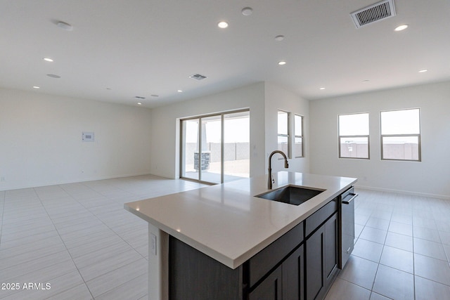 kitchen with a kitchen island with sink, sink, dishwasher, and light tile patterned floors