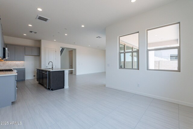 kitchen with backsplash, sink, a center island with sink, dishwasher, and gray cabinets