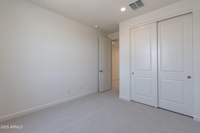 unfurnished bedroom featuring light colored carpet and a closet