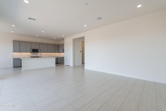 unfurnished living room featuring sink and light tile patterned flooring