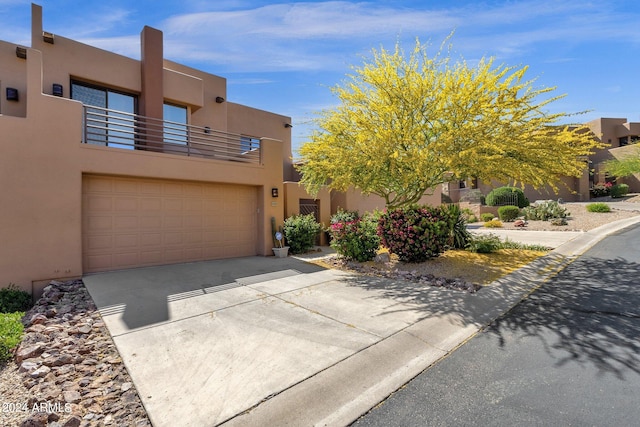 pueblo revival-style home featuring a garage and a balcony