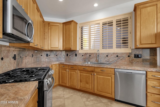 kitchen featuring backsplash, sink, light tile patterned floors, and appliances with stainless steel finishes