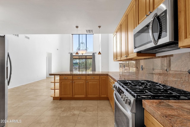 kitchen featuring kitchen peninsula, pendant lighting, decorative backsplash, light tile patterned flooring, and appliances with stainless steel finishes