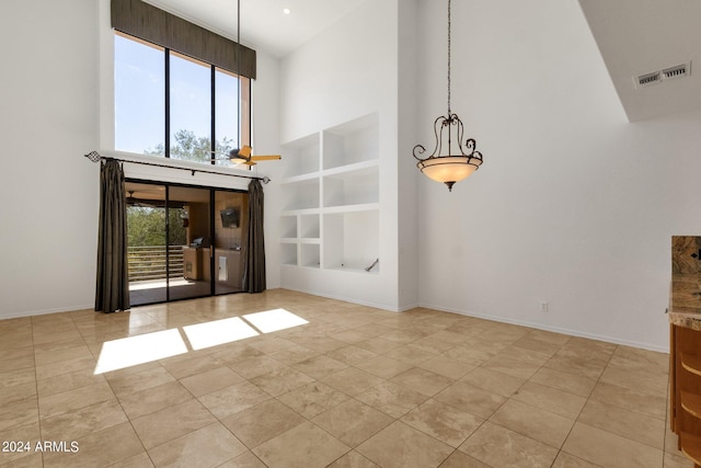 unfurnished living room with built in features, high vaulted ceiling, a healthy amount of sunlight, and light tile patterned floors