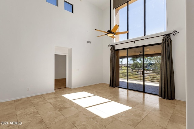 unfurnished living room with a wealth of natural light, ceiling fan, light tile patterned floors, and a high ceiling