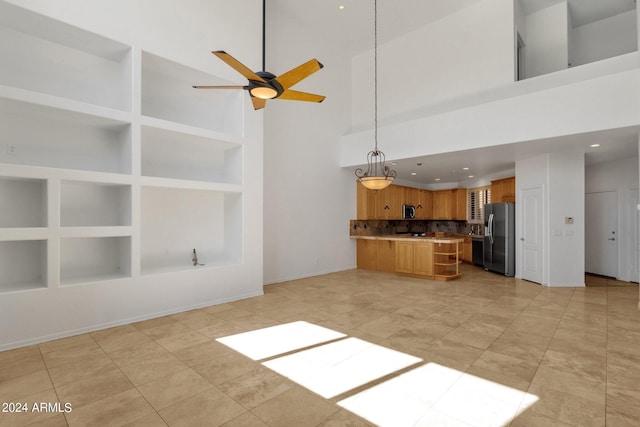 unfurnished living room featuring built in shelves, ceiling fan, a towering ceiling, and light tile patterned floors