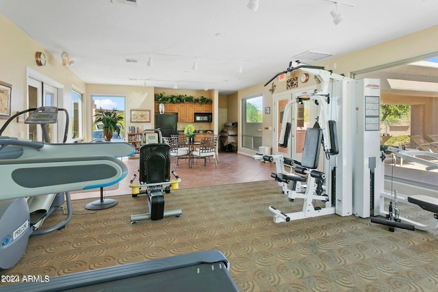 gym with rail lighting and light tile patterned floors