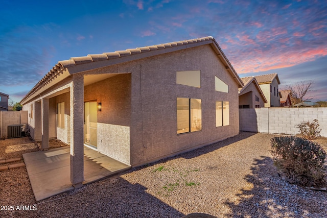 back house at dusk featuring central air condition unit and a patio