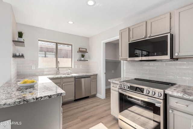 kitchen featuring backsplash, light hardwood / wood-style floors, gray cabinetry, and stainless steel appliances