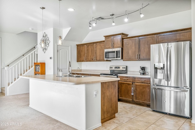 kitchen with appliances with stainless steel finishes, sink, an island with sink, and hanging light fixtures