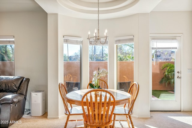 carpeted dining space featuring an inviting chandelier and a tray ceiling