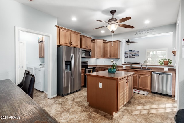 kitchen with stainless steel appliances, ceiling fan, sink, independent washer and dryer, and a center island