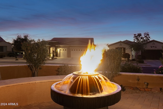 patio terrace at dusk featuring a garage