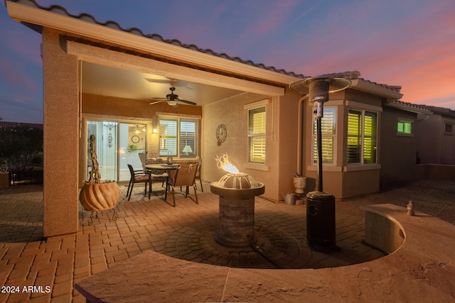 patio terrace at dusk with a fire pit and ceiling fan