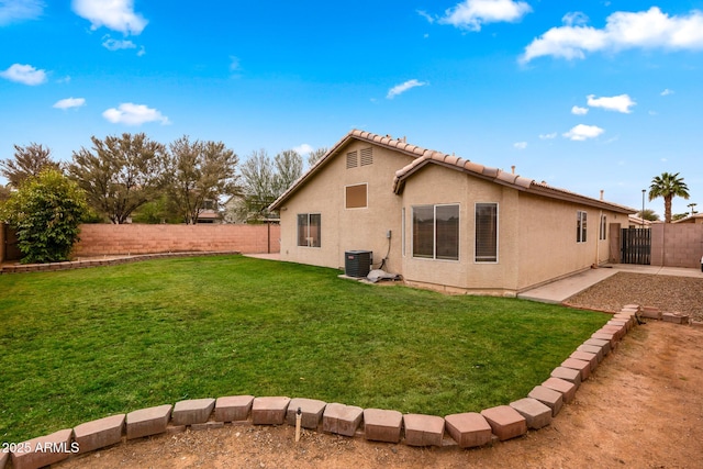 back of house with central AC unit and a yard