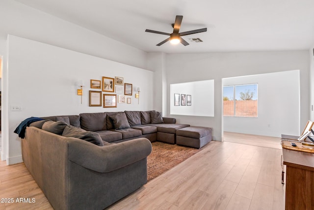 living room with vaulted ceiling, ceiling fan, and light wood-type flooring