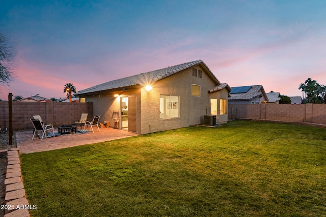 back house at dusk featuring central AC, an outdoor fire pit, a yard, and a patio area