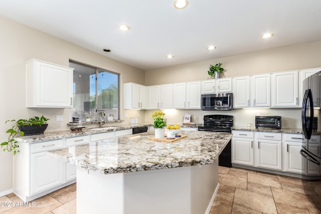 kitchen with white cabinets, light stone countertops, a kitchen island, and stainless steel appliances