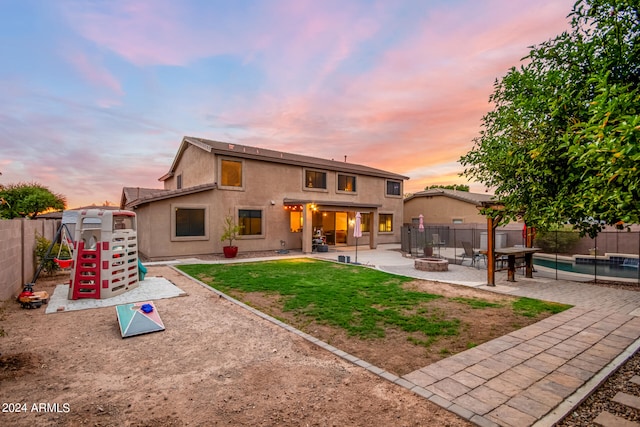 back house at dusk with a fire pit, a pool, and a patio area