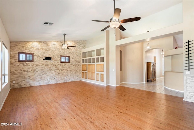 unfurnished living room featuring high vaulted ceiling, ceiling fan, and light hardwood / wood-style flooring