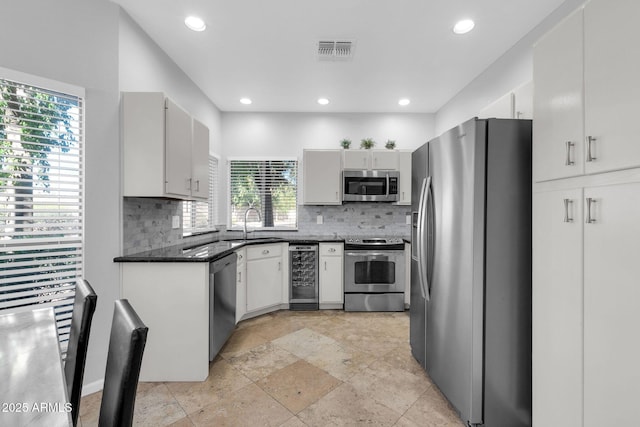 kitchen with appliances with stainless steel finishes, sink, beverage cooler, and decorative backsplash