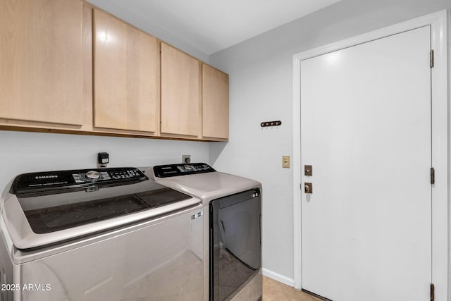 clothes washing area with cabinets, light tile patterned flooring, and washer and clothes dryer