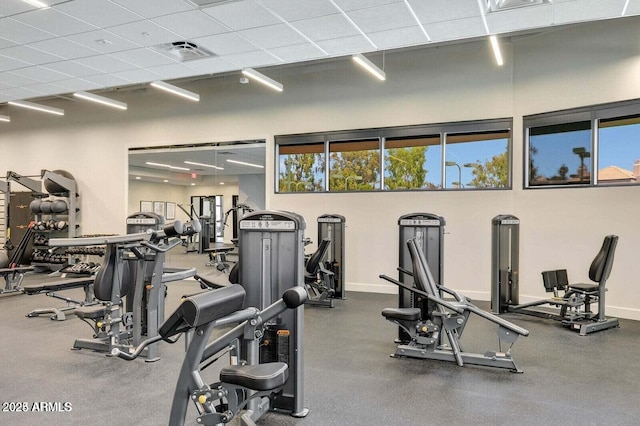 gym featuring a paneled ceiling and a healthy amount of sunlight