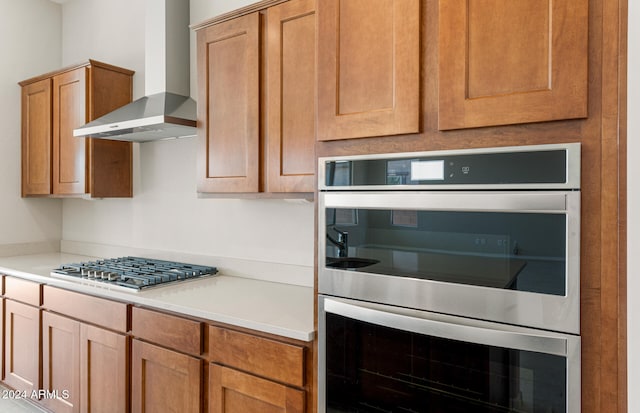 kitchen featuring wall chimney range hood and stainless steel appliances